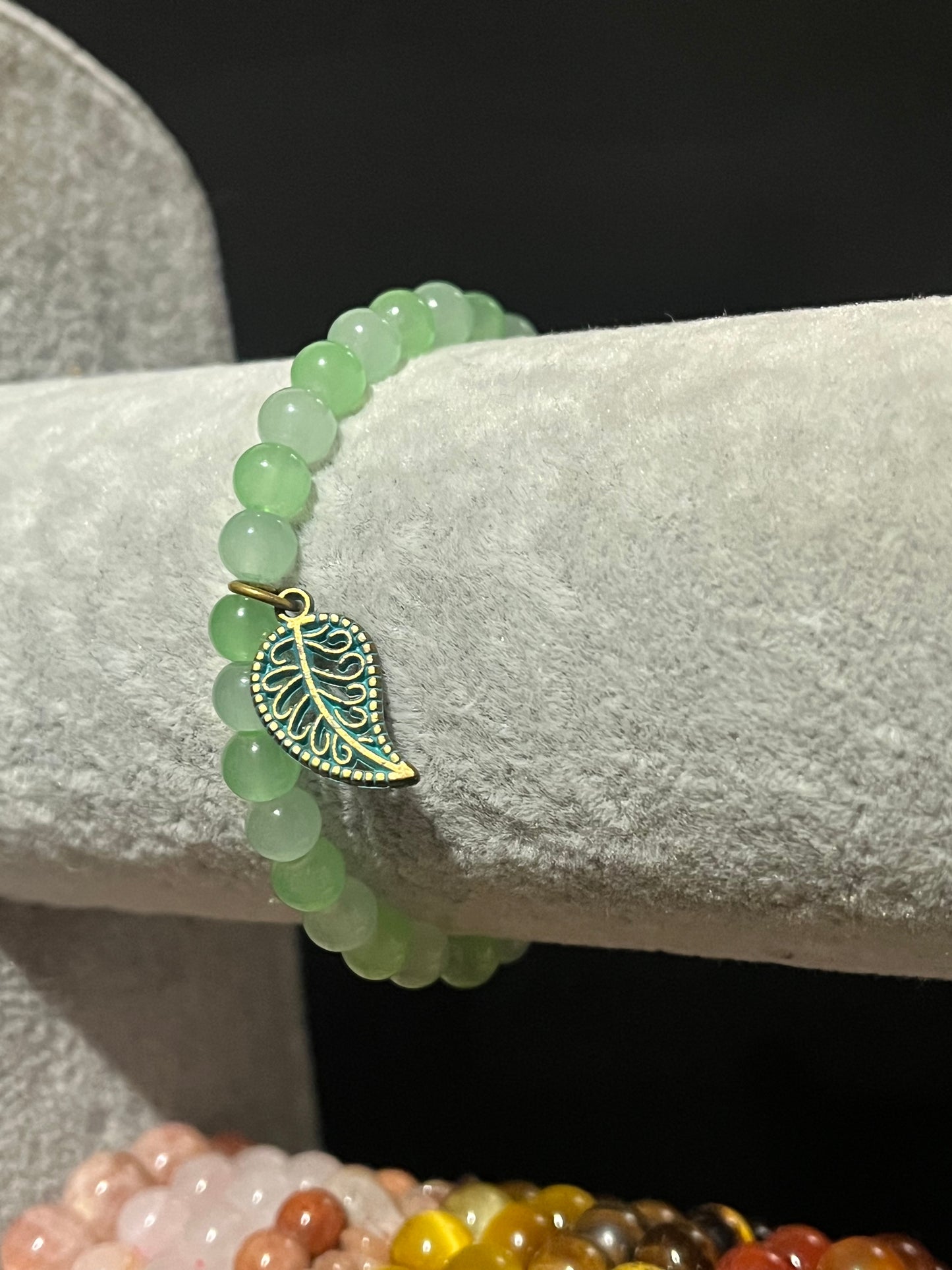 Green bracelet with gold leaf charm.