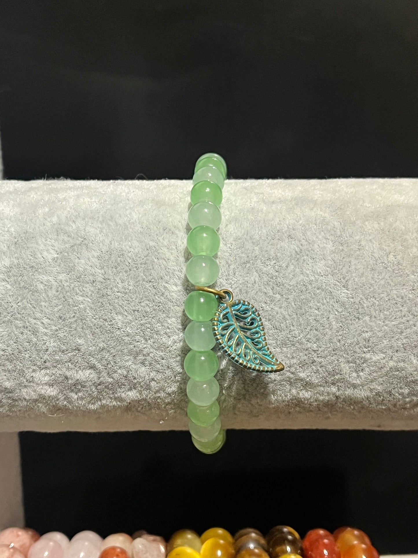 Green bracelet with gold leaf charm.