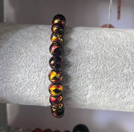 Black bracelet with gold and red accents